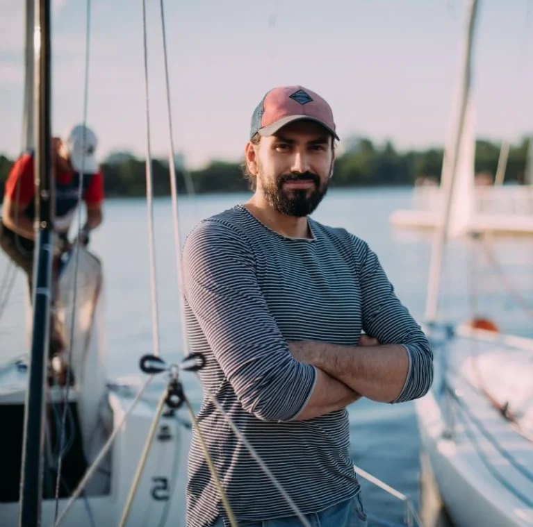 Skipper steht im Hafen vor einer Segelyacht