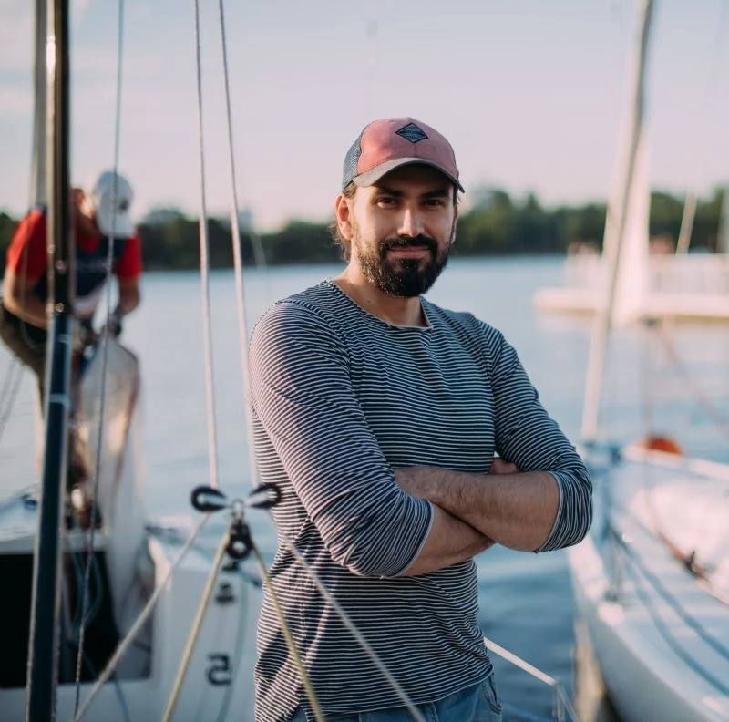 Skipper steht im Hafen vor einer Segelyacht